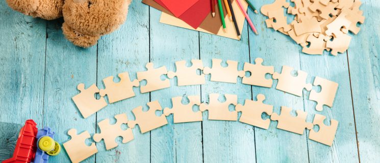 Concept of mock up and pieces of puzzles on the background of wooden table. Education, school, family, baby, pregnancy, maternity, parenting, children concepts